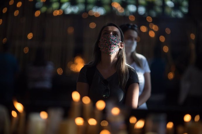 12 October 2020, Brazil, Aparecida: Awoman prays in the candle room of Our Lady of Aparecida Basilica, on the feast day of Nossa Senhora Aparecida, the patron saint of Brazil. The feast masses had to be celebrated by small number of people due to the C
