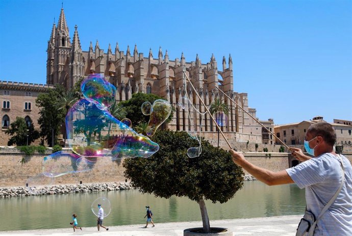 Un hombre hace pompas de jabón en el Parc de la Mar, frente a la Catedral.