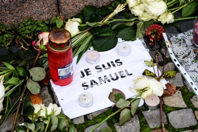 27 October 2020, Berlin: A sign reading "I am Samuel Paty' is seen among flowers and candles placed in front of the French embassy in Berlin. French teacher Samuel Paty was beheaded in a suburb outside Paris earlier this month for showing cartoons of Is