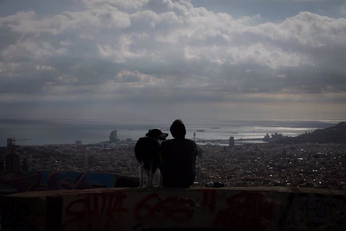 Un joven mira el paisaje en el mirador Turó de la Rovira, en Barcelona