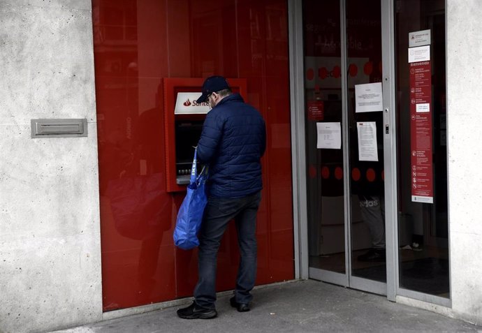 Un hombre saca dinero de un cajero del Banco Santander 