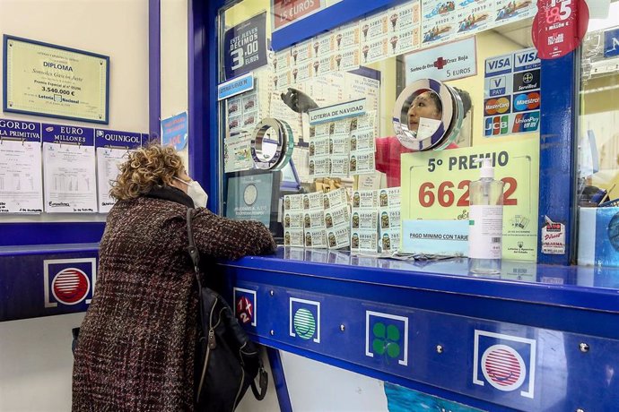 Una persona compra en la administración de lotería La Pajarita donde se venden boletos para el Sorteo Extraordinario de la Lotería de Navidad 2020, Madrid (España)