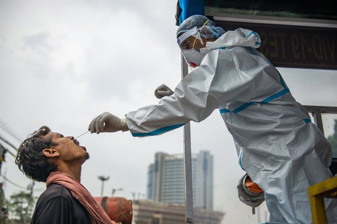 Un trabajador sanitario realiza un test a un ciudadano indio.