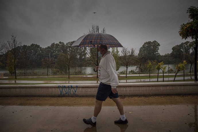 Un hombre camina protegido de la lluvia con un paraguas. 