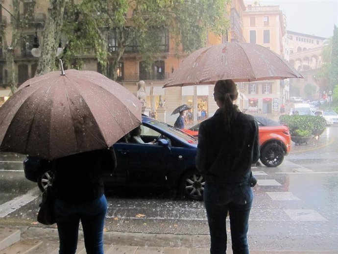 Dos personas con paraguas para cubrirse de la fuerte lluvia en el Paseo del Borne de Palma.