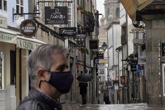 Un hombre camina por una calle con establecimientos cerrados durante el primer día de cierre en la hostelería decretado debido a la crisis del Covid-19, en Santiago de Compostela