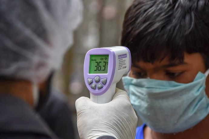 Imagen de recurso de un trabajador sanitario tomando la temperatura a un hombre en India.
