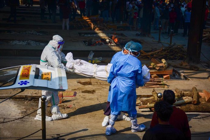 Sanitarios indios llevan el cuerpo de una víctima de la COVID-19 al crematorio de Nigambodh Ghat, en Nueva Delhi, India. 