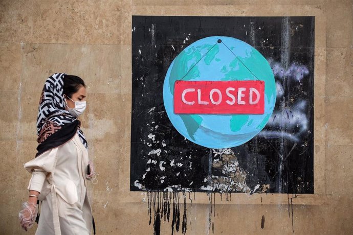 Una mujer ante un graffiti en la capital de Irán, Teherán, durante la pandemia de coronavirus