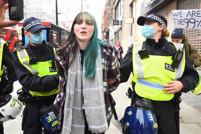 La Policía de Londres detiene a una manifestante contra las restricciones por la pandemia de COVID-19.