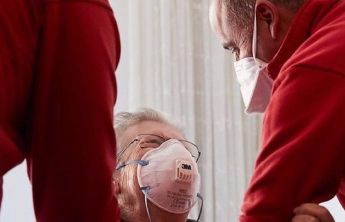 Voluntarios de Cruz Roja ayudan a una mujer mayor.