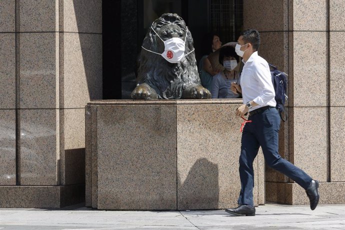Un hombre y una estatua de un león con mascarilla en Tokio, Japón