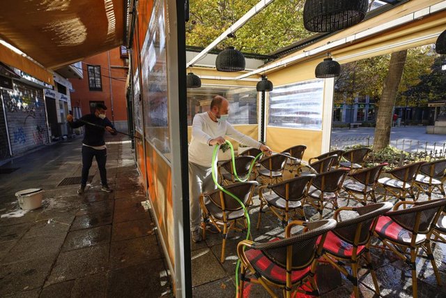 Camareros limpiando y poniendo las mesas en las terrazas de los bares a primera hora de las mañana, tras rebajar la Junta de Andalucía las restricciones anteriores que mantenían cerrado los negocios durante todo el día