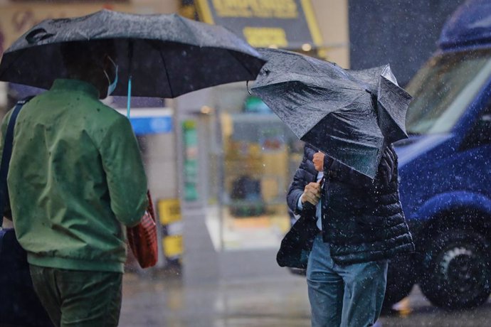 Transeúntes caminan por el centro de la capital en una jornada marcada por las lluvias y la bajada de temperaturas.