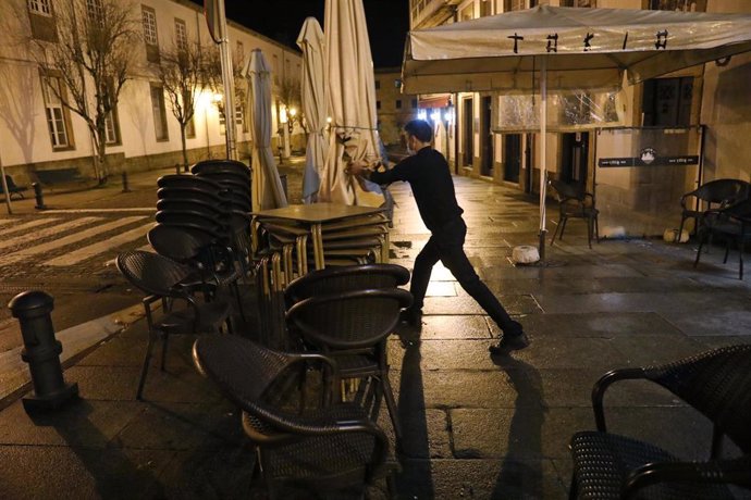 Un camarero recoge la terraza de su establecimiento a la hora del cierre tras las medidas ordenadas por la crisis del Covid-19, en Santiago de Compostela, Galicia, (España), a 6 de noviembre. La hostelería permanece cerrada desde las 00,00 horas de este
