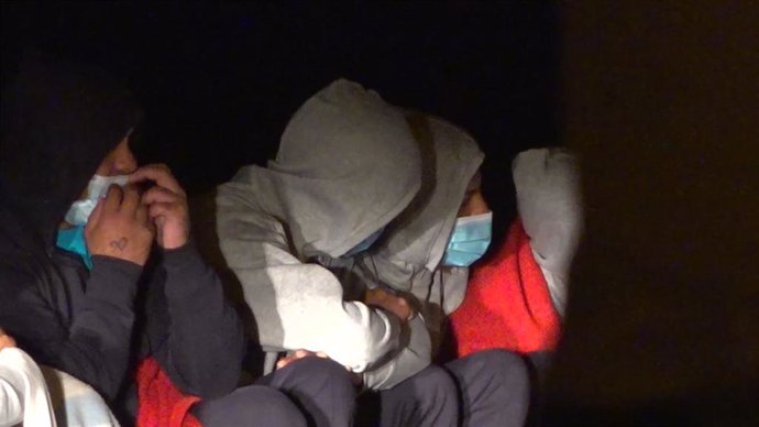 Tapadas con mantas de Cruz Roja. algunas de las 27 personas que lograron llegar a tierra con vida tras el vuelco de la patera en la que viajaban en la noche de este martes,  en la costa de Órzola, en la zona de La Condesa, en Lanzarote, Canarias (España