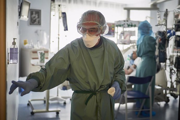 Un trabajador sanitario totalmente protegido sale de una habitación de la UCI de la Clínica Universidad de Navarra, en Pamplona