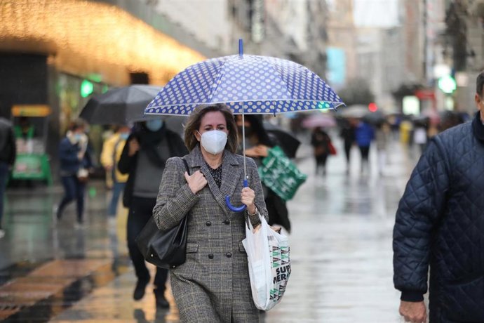 Una mujer pasea protegida con un paraguas por el centro de la capital, en Madrid, (España), a 27 de noviembre de 2020. El año hidrológico, que comenzó el 1 de octubre, acumula hasta el 24 de noviembre un 16 por ciento menos lluvias de lo normal, según d