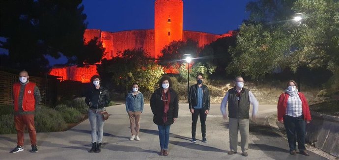 Representantes de la Mesa por el Sida frente al Castillo de Bellver, iluminado de rojo por el Día Mundial de la Lucha contra esta enfermedad.