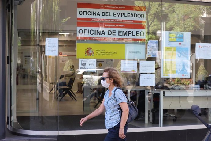 Una mujer con mascarilla pasa por una oficina de empleo de Madrid.