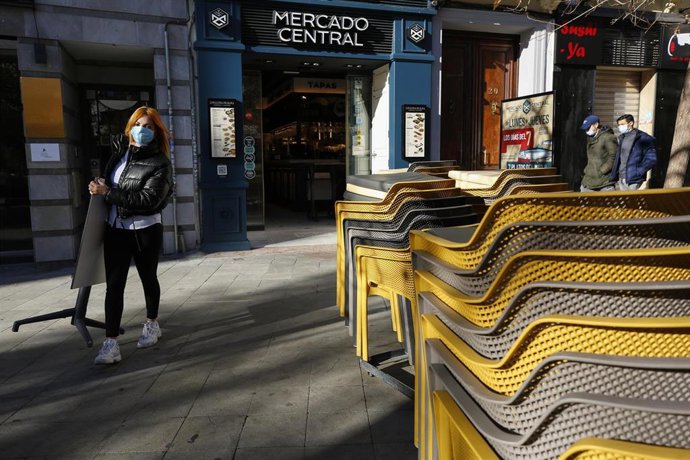 Camarera de un bar coloca las mesas de una terraza 