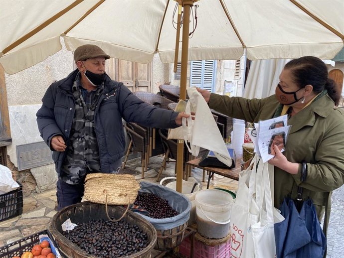 La consellera Mae de la Concha repartiendo bolsas y mascarillas entre los vendedores de producto local en el mercado de Sineu.