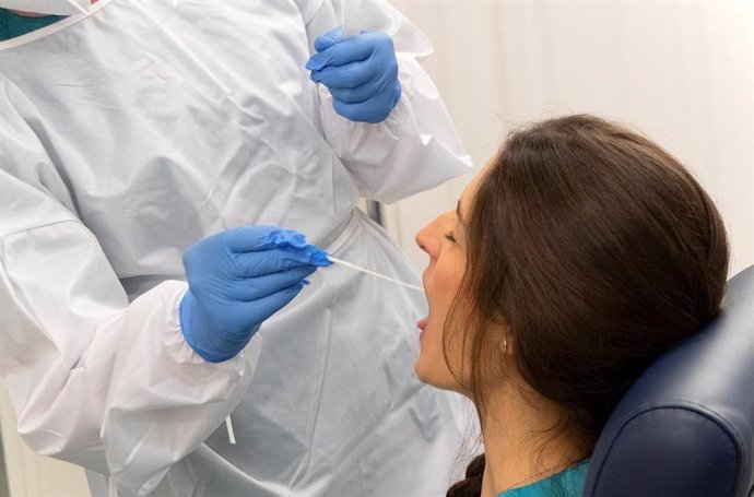 Un sanitario toma muestras de una mujer para hacer una PCR.