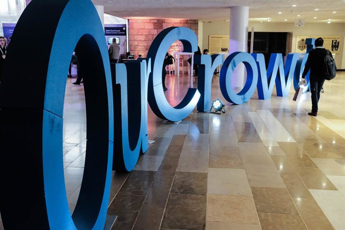 07 March 2019, Israel, Jerusalem---: A visitor walks by the logo of "OurCrowd" during the 2019 OurCrowd Global Investor Summit. Photo: Nir Alon/ZUMA Wire/dpa