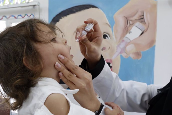 Una trabajadora sanitaria da una dosis de la vacuna contra la polio a una niña en Yemen.