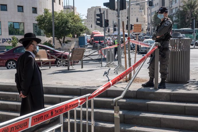 Un policía de Israel junto a un hombre en Jerusalén durante la pandemia de coronavirus