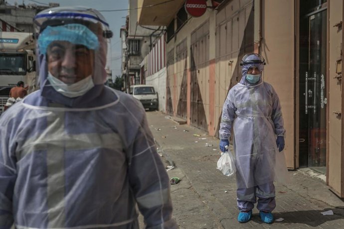 01 September 2020, Palestinian Territories, Gaza City: United Nations Relief and Works Agency for Palestine Refugees (UNRWA) employees wearing protective clothes distribute medicines to those with chronic diseases during the outbreak of the Coronavirus 