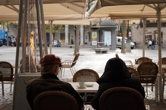 Dos personas disfrutan en la terraza de un establecimiento el mismo día de la reapertura de la hostelería tras la relajación de las restricciones decretadas por la Junta para las provincias de Ávila y Segovia, en Segovia, Castilla y León, (España).