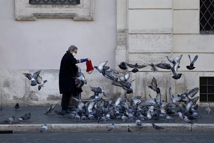 23 November 2020, Italy, Rome: A woman wearing a face mask feeds the pigeons. Photo: Cecilia Fabiano/LaPresse via ZUMA Press/dpa