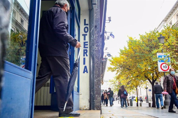 Una persona sale de la administración de lotería La Pajarita donde venden boletos para el Sorteo Extraordinario de la Lotería de Navidad 2020, en Madrid (España).