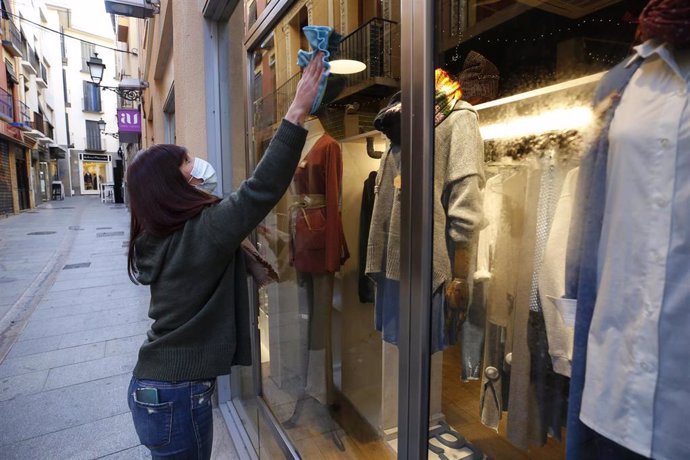 Una dependienta limpiando un escaparate de una tienda