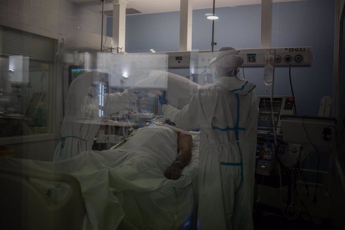 Trabajadores sanitarios protegidos atienden a un paciente en la UCI