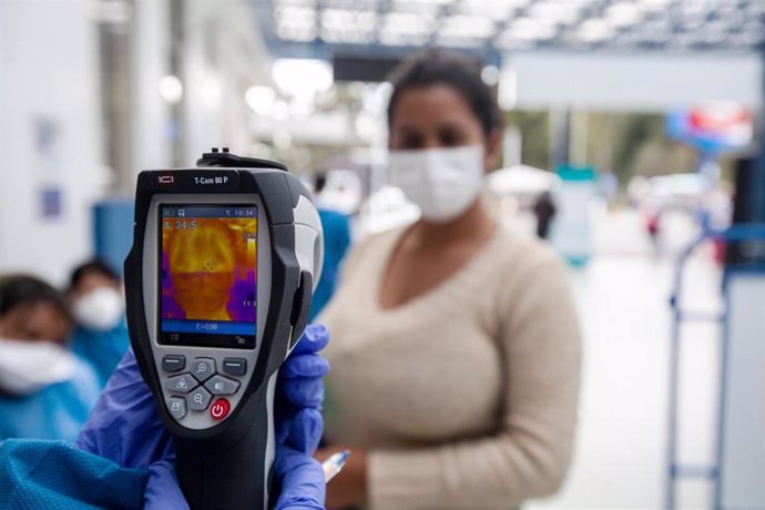 Un trabajador sanitario toma la temperatura de una mujer colombiana.