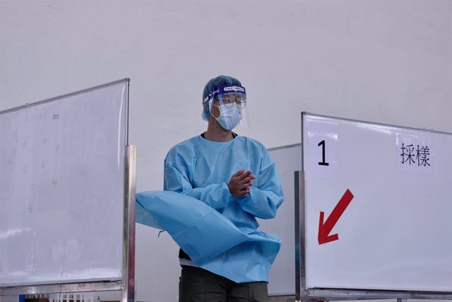 04 December 2020, China, Hong kong: A medical worker in protective gear rubs disinfectant into his hands as he stands in a temporary cubicle for a coronavirus test station. Photo: Liau Chung-Ren/ZUMA Wire/dpa