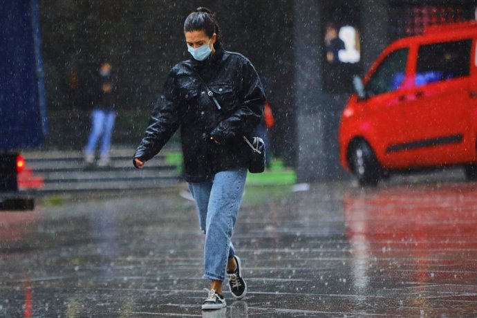 Una persona camina por la calle en una jornada marcada por las lluvias y la bajada de temperaturas.