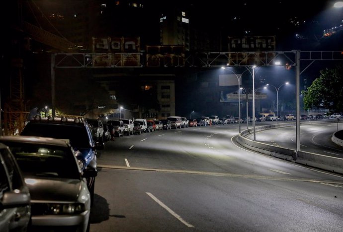 22 April 2020, Venezuela, Caracas: People stand beside their cars in long queue in front of a gas station. The largest Russian oil company Rosneft, one of the last and largest foreign investors in Venezuela, has withdrawn from the South American country