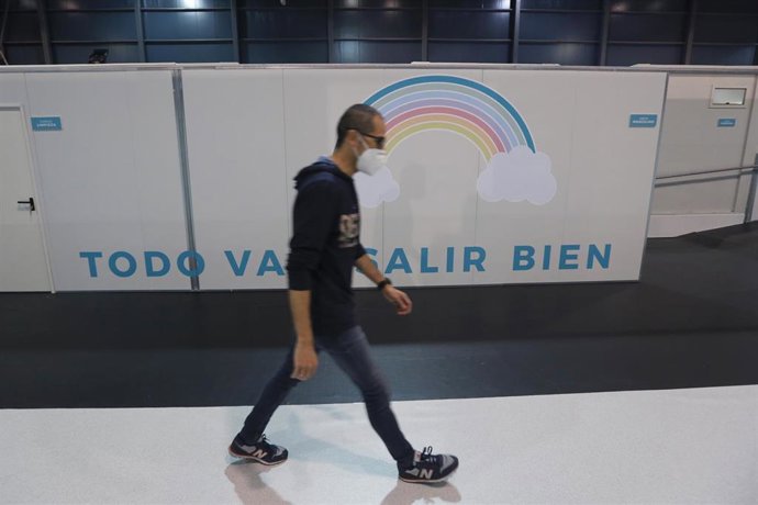 Un hombre pasa por un arcoiris con la frase 'Todo va a salir bien' en el hospital provisional H144 que se ha montado en el recinto ferial gijonés 'Luis Adaro', el día de su inauguración en Gijón, Asturias (España), a 11 de noviembre de 2020. Es la segun