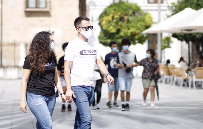 Dos personas con mascarilla caminan por la Plaza de España de Mérida.