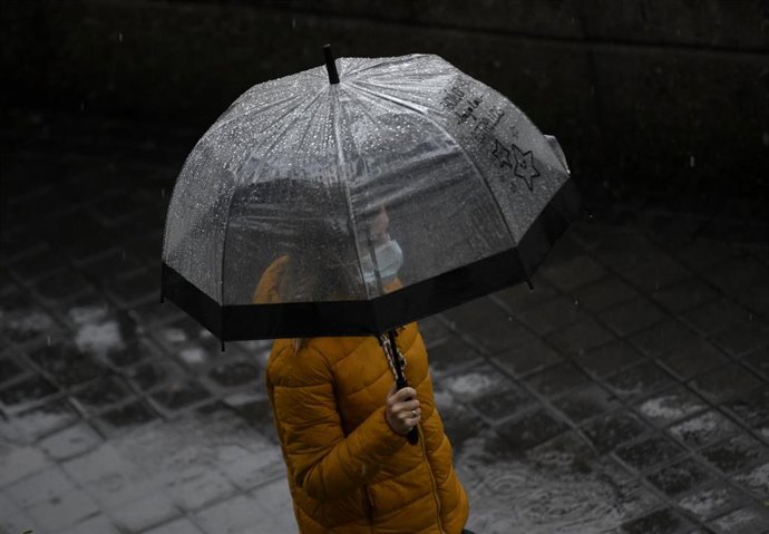 Imagen de archivo. Una persona camina bajo la lluvia protegida con un paraguas
