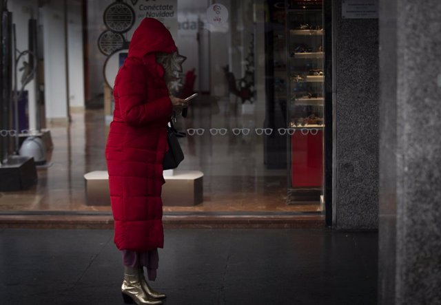 Una mujer bajo un soportal espera que cese la lluvia