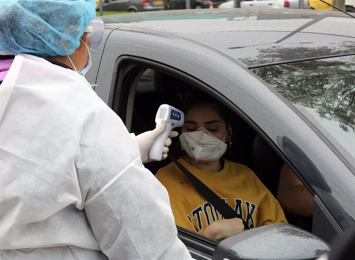 Una trabajadora médica tomando la temperatura a una mujer colombiana en el contexto de la pandemia del coronavirus.