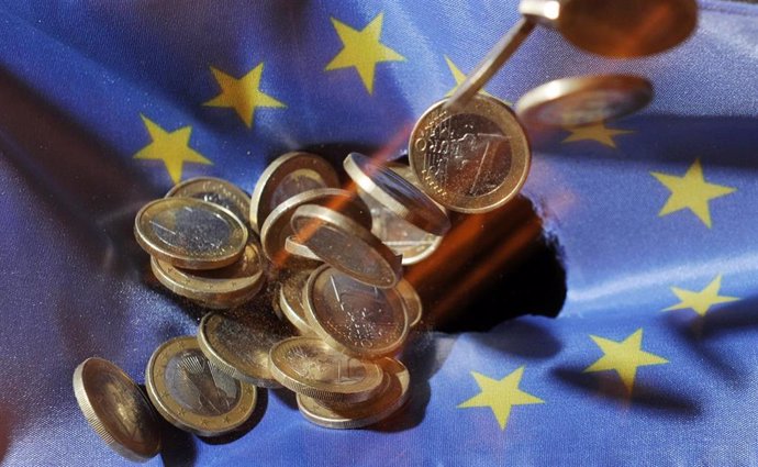 FILED - 04 July 2011, Baden-Wuerttemberg, Karlsruhe: One euro coins will fall onto an EUflag. The European Union's gross domestic product shrank 3.5 per cent in the first three months of the year, according to a first estimate from Eurostat, while euro