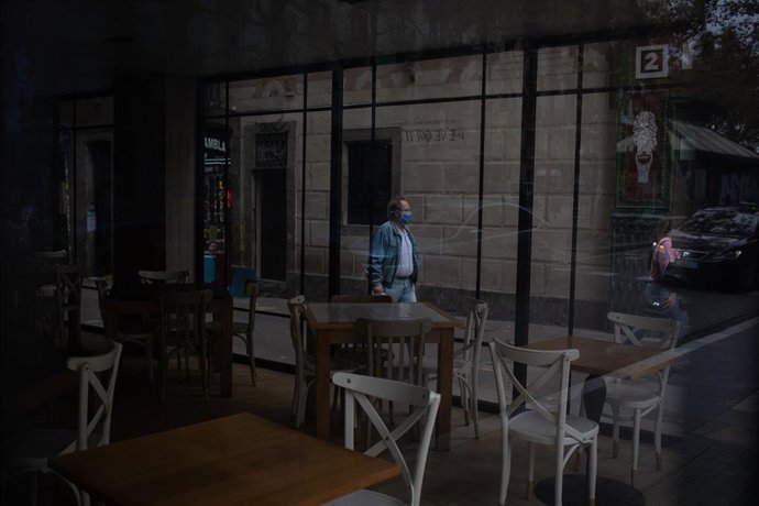 Un hombre camina por la calle frente a una cafetería en Barcelona.