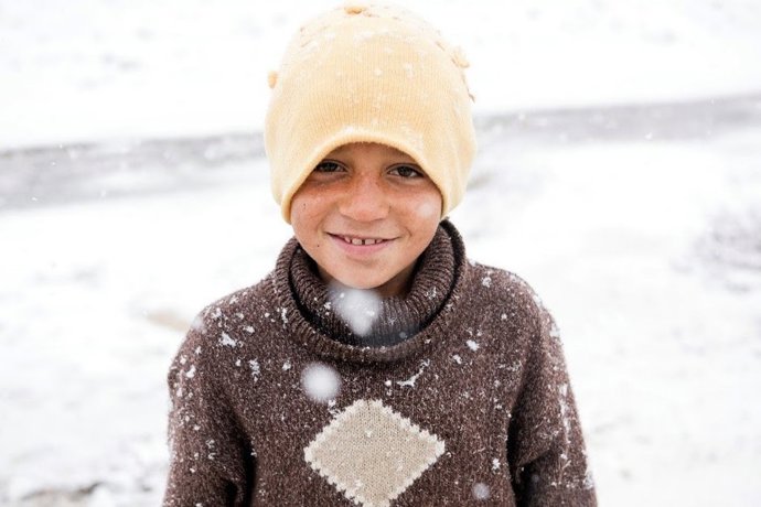 Niño refugiado en invierno, entre la nieve.