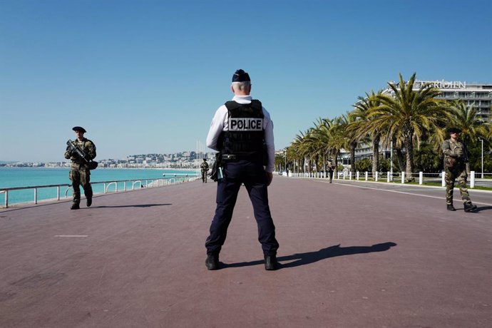 18 March 2020, France, Nizza: A policeman stands by while soldiers patrol the famous "Promenade des Anglais" on the French Riviera. A nationwide 15-day curfew has been in force in France since noon on Tuesday. Photo: Valery Hache/AFP/dpa