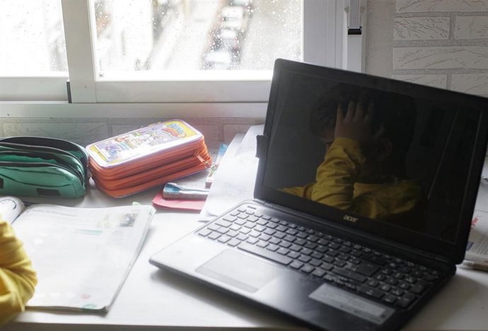 Reflejo en un ordenador portátil de un niño estudiando y haciendo los deberes en casa 